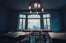 Warmly lit room with rustic wooden furniture and a view of misty mountain peaks.