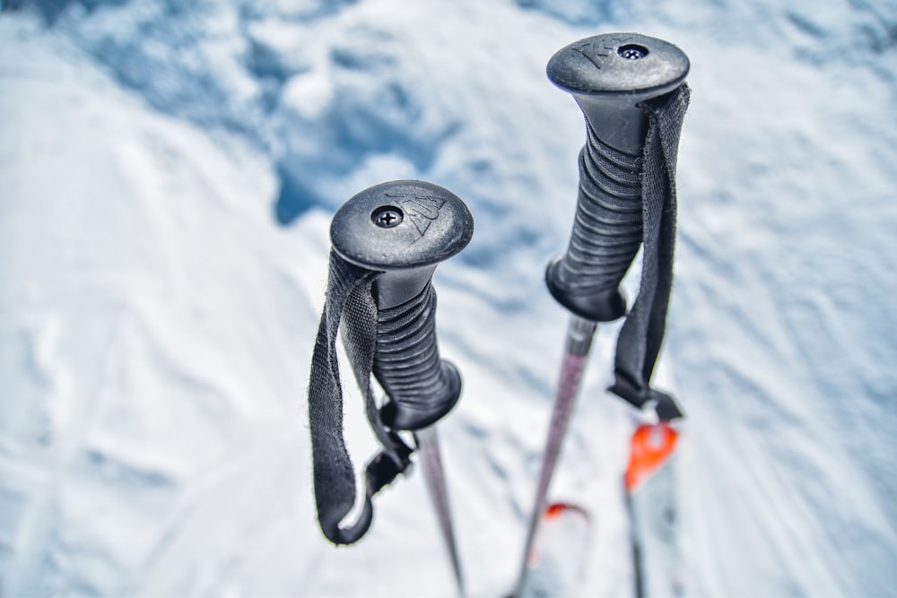 Two black ski poles stuck in the snow in winter