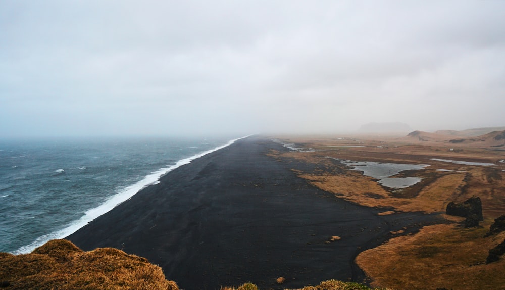 sable brun et noir près de l’océan pendant la journée