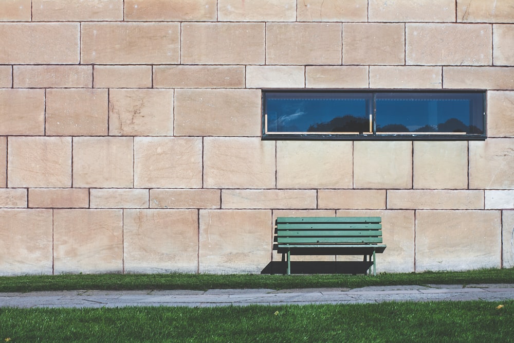 green wooden bench near wall