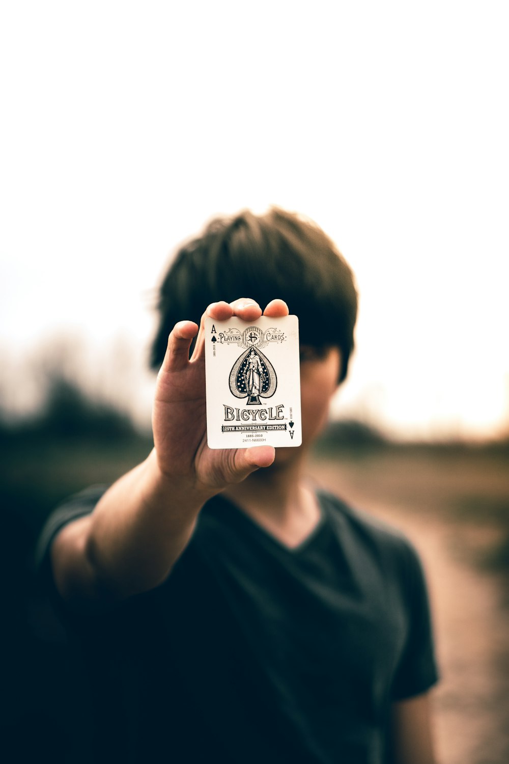 selective focus photography of person holding ace of spades card