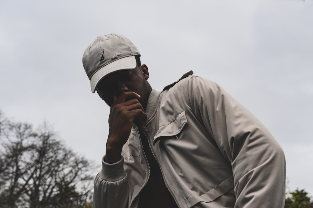 hombre con chaqueta gris y gorra bajo las nubes grises