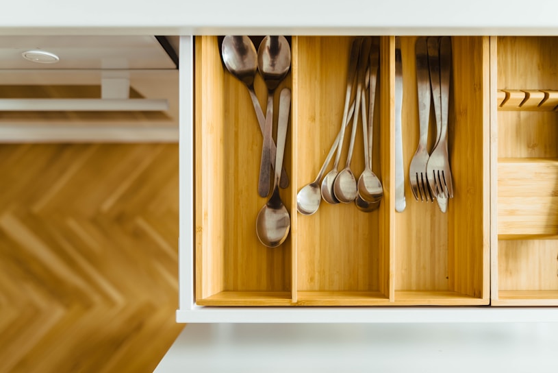 A neatly arranged kitchen drawer with frostda's wooden drawer organizer trays holding utensils and spices.