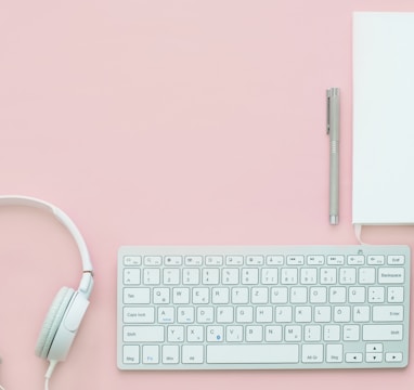 white Apple Magic Mouse beside of Magic Keyboard and headphones