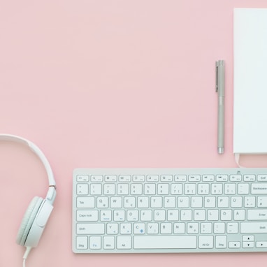 white Apple Magic Mouse beside of Magic Keyboard and headphones