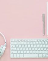 white Apple Magic Mouse beside of Magic Keyboard and headphones