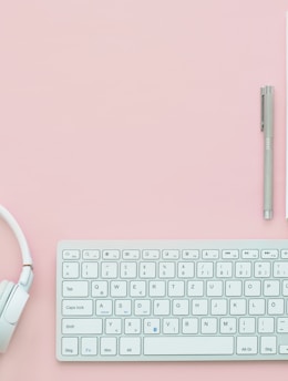 white Apple Magic Mouse beside of Magic Keyboard and headphones