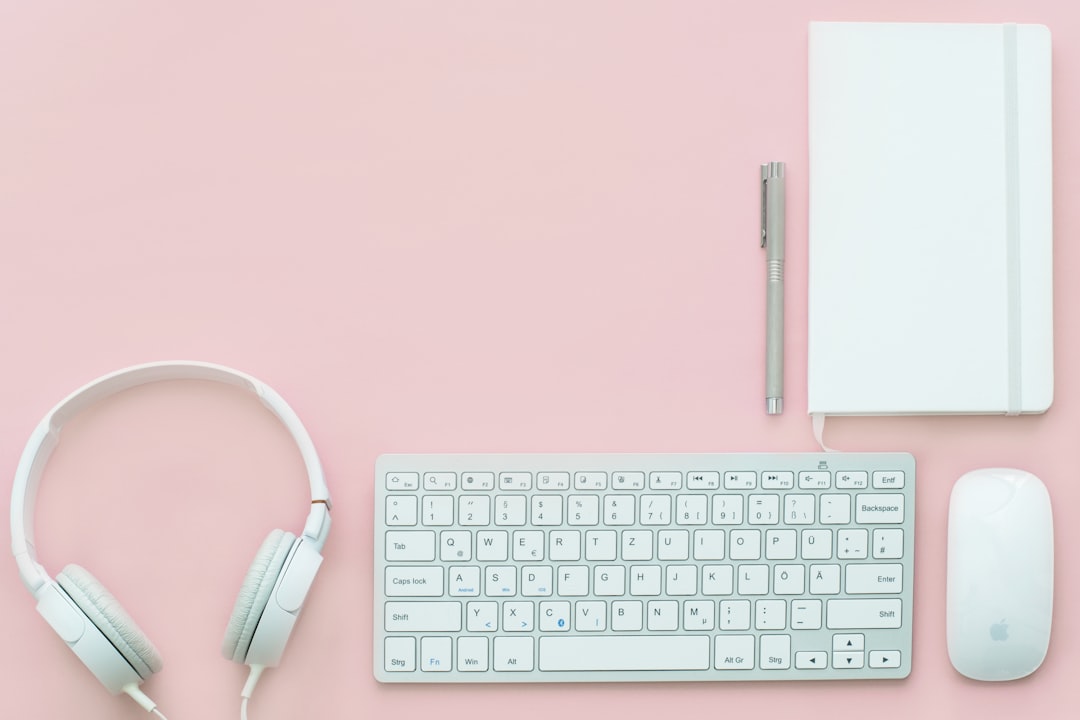 white Apple Magic Mouse beside of Magic Keyboard and headphones, White gear on pink flatlay