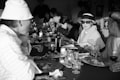 A group of people dining together with blindfolds, sharing laughter and enjoying mysterious dishes.