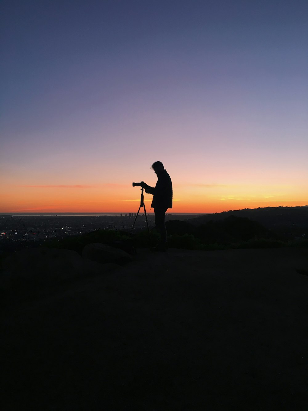 silhouette d’homme devant l’appareil photo reflex numérique pendant l’heure dorée