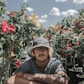 man sitting near hibiscus flowers during daytime