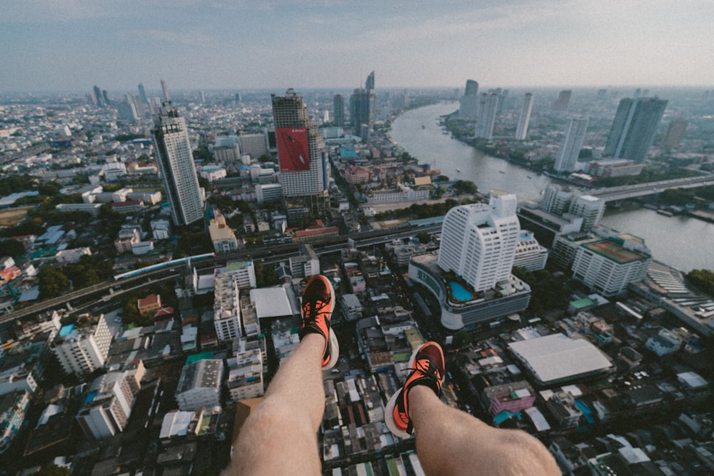 man paragliding taking aerial photography of city scapes during daytime