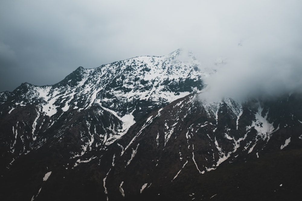 mountain covered with snow and surrounded with clouds