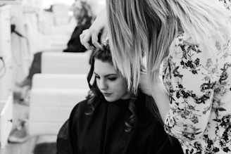 grayscale photography of woman getting her hair done inside salon