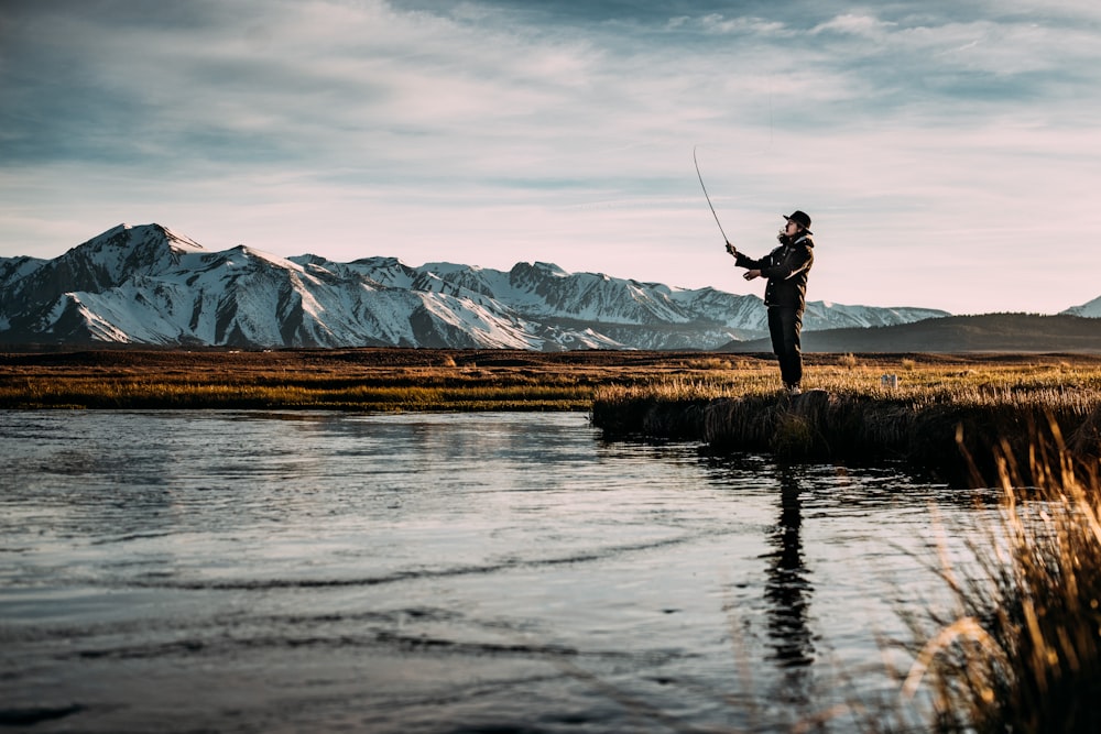 Photo de paysage d’un homme pêchant sur une rivière près des Alpes de montagne