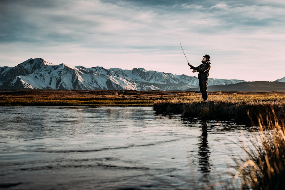 アルプス山近くの川で釣りをしている男の風景写真