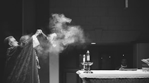 A moment during holy mass with incense rising, attended by the handmaids and a priest.