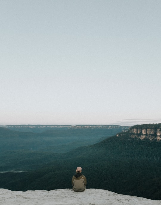 person sitting on rock while sight seeing in Blue Mountains Australia