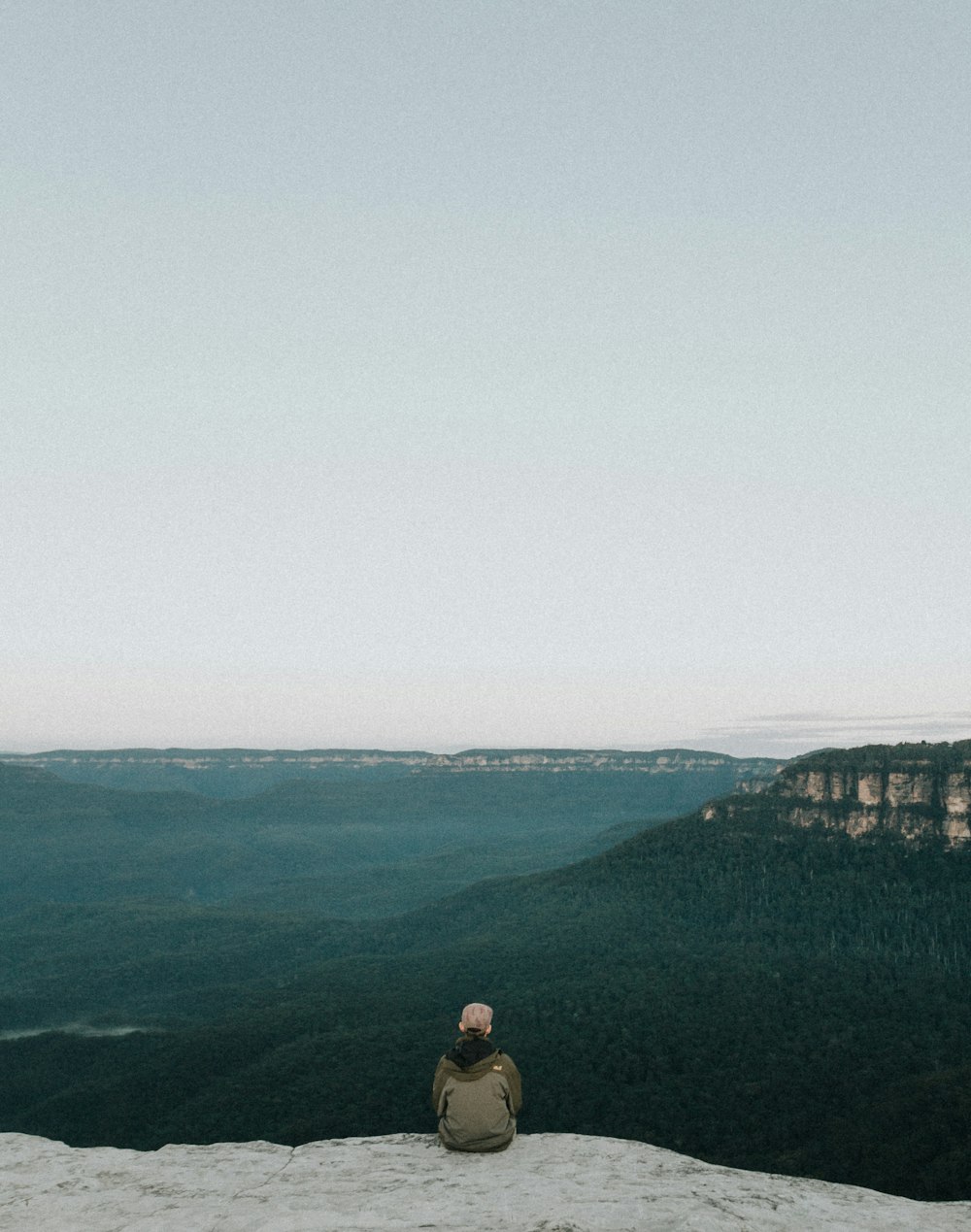 persona sentada en la roca mientras hace turismo