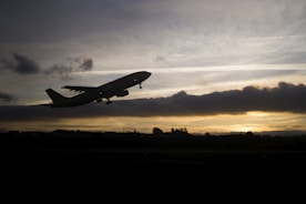 An airplane taking off against a sunset backdrop.