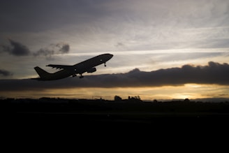 An airplane taking off against a vibrant sunset backdrop.