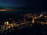 A dramatic aerial drone shot of Akşehir's historic town center with rooftops and streets bathed in soft twilight.