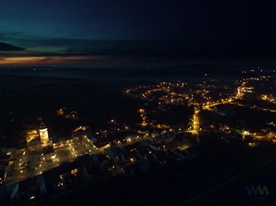 A dramatic aerial drone shot of Akşehir's historic town center with rooftops and streets bathed in soft twilight.