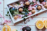 A rustic wooden tray with an assortment of pastries and a small vase with fresh flowers.