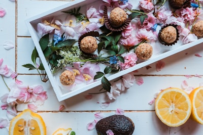 A rustic wooden tray with an assortment of pastries and a small vase with fresh flowers.