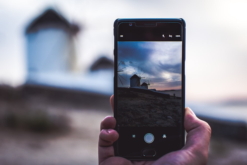 Mann mit Telefon macht Foto vom Haus