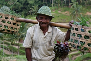 A farmer smiling warmly while holding a basket full of freshly harvested produce