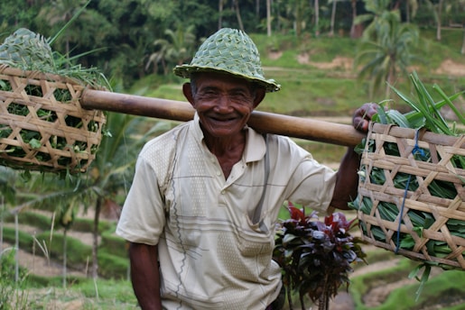 Close-up of a smiling Indonesian farmer carefully tapping a sugar palm tree at dawn.