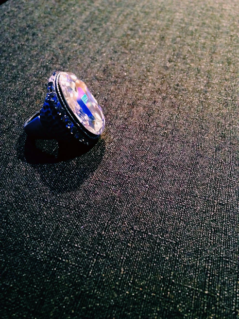 Hand holding a shiny resin ring glistening under sunlight