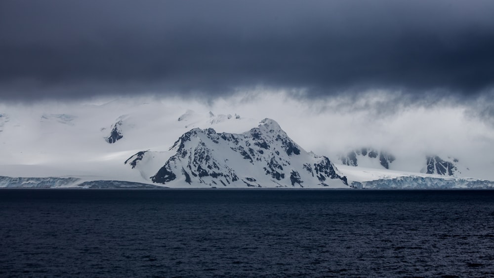 snow-covered mountain near body of water