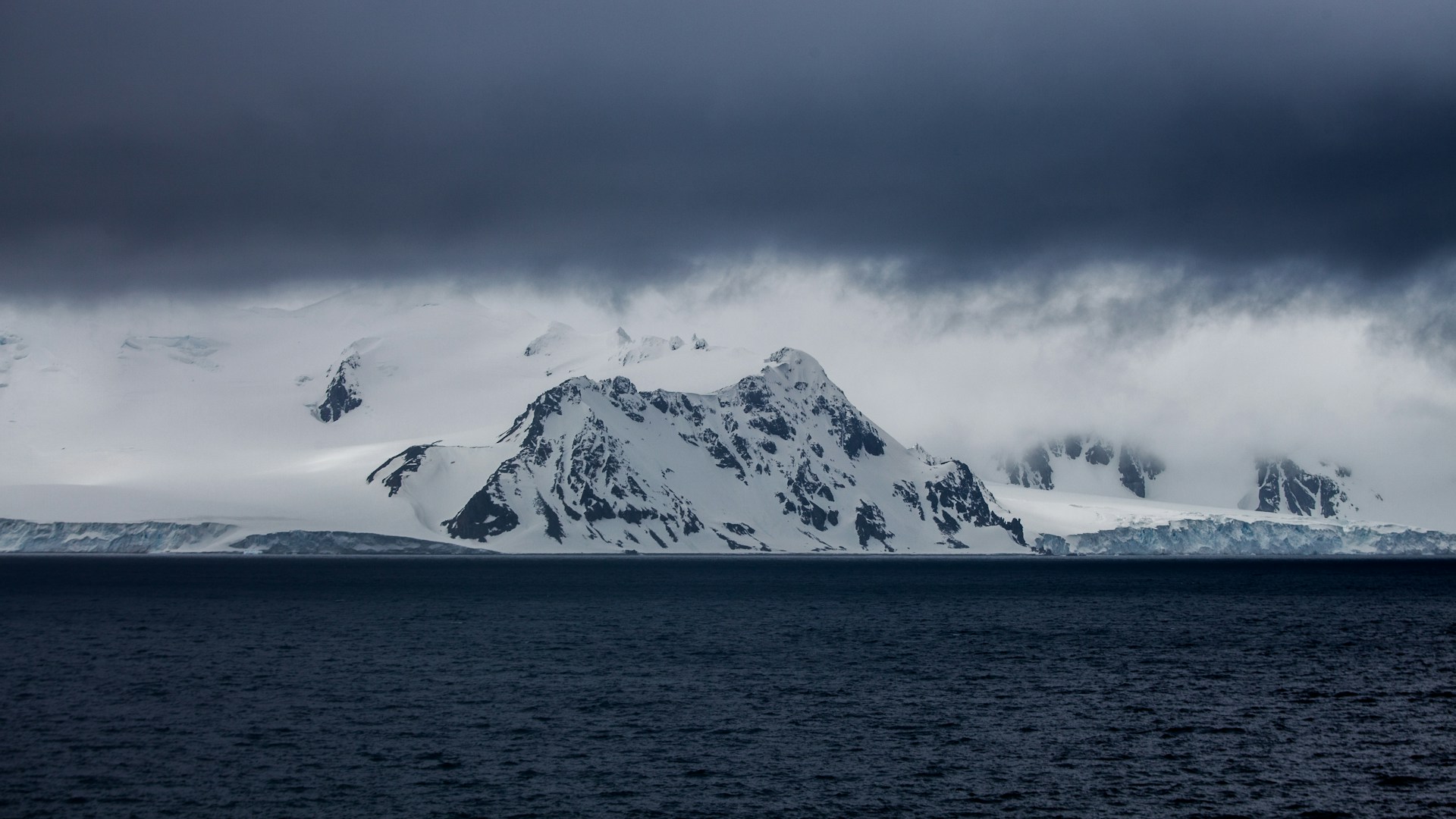 snow-covered mountain near body of water