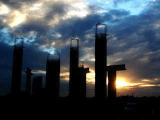 Metro viaduct pillars rising above a busy cityscape during sunset.