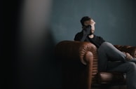 a man holds his head while sitting on a sofa