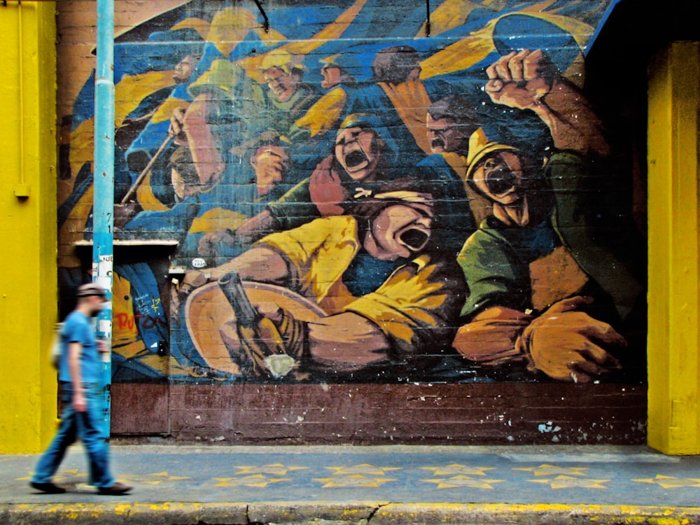 hombre caminando al lado de la obra de arte del graffiti