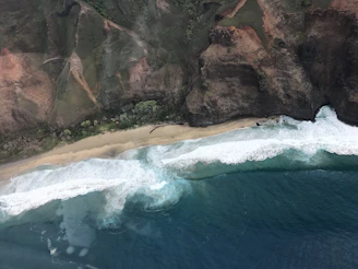 A sweeping view of a rugged coastline under a deep blue sky, waves crashing against jagged cliffs.