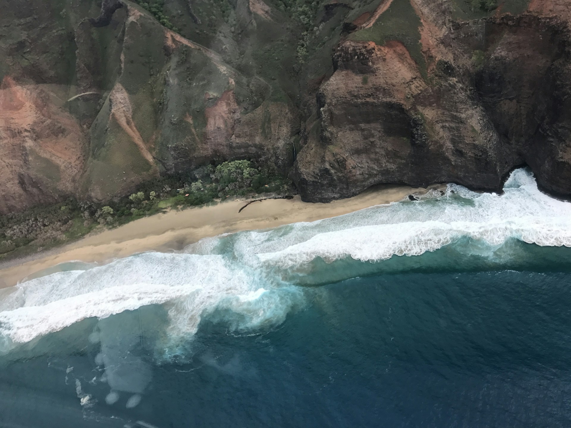An expansive view from above of a rugged coastline with crashing waves and rocky cliffs.