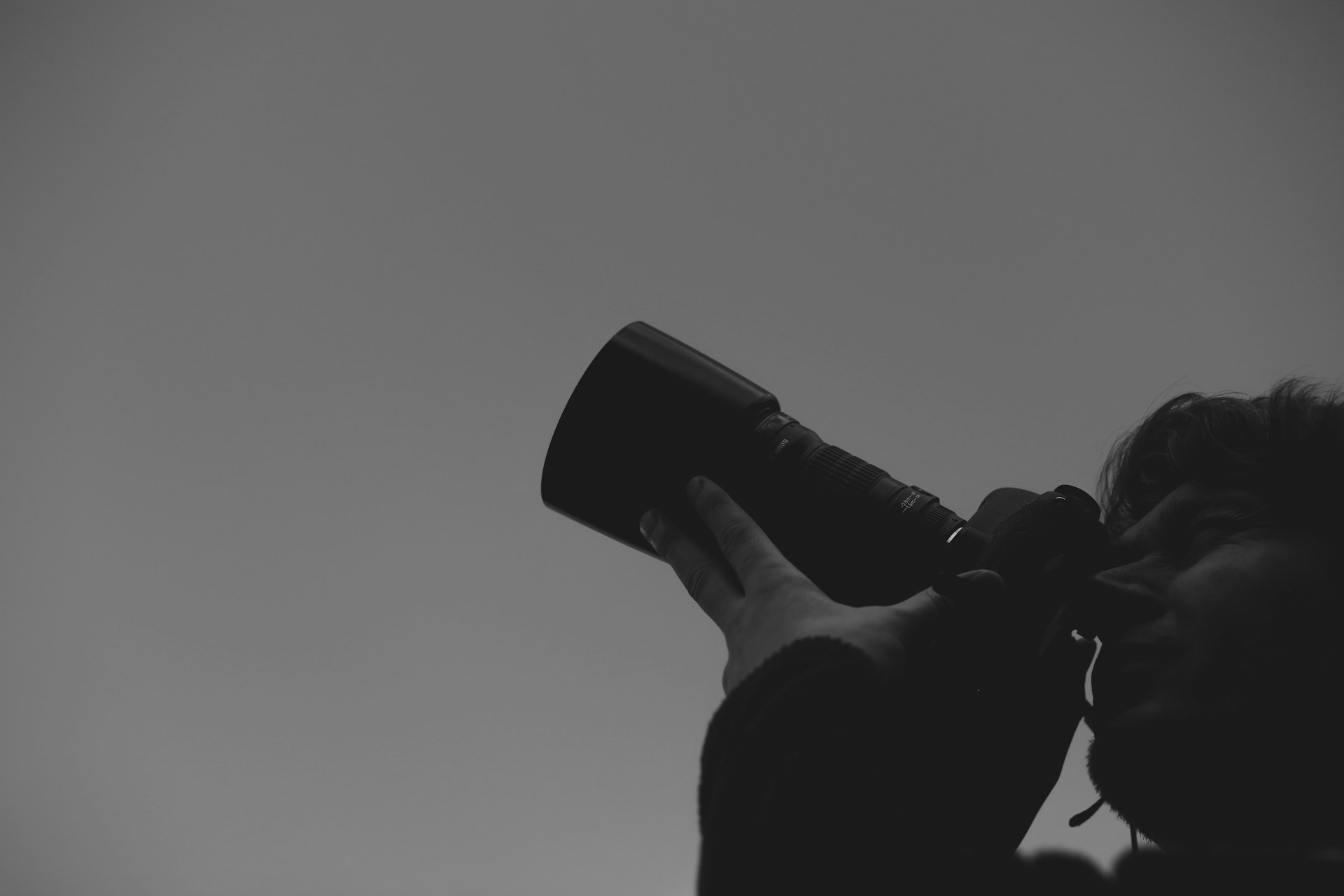 a black and white photo of a person holding a camera