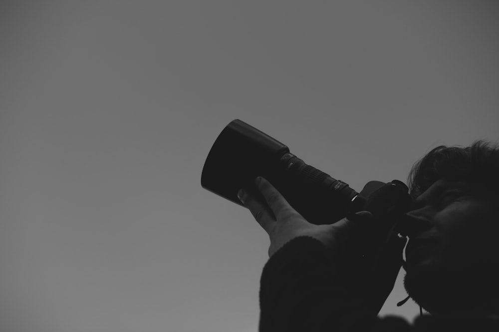 a black and white photo of a person holding a camera