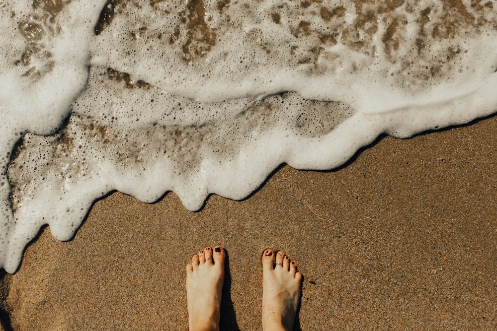 los pies de una persona en la orilla del mar