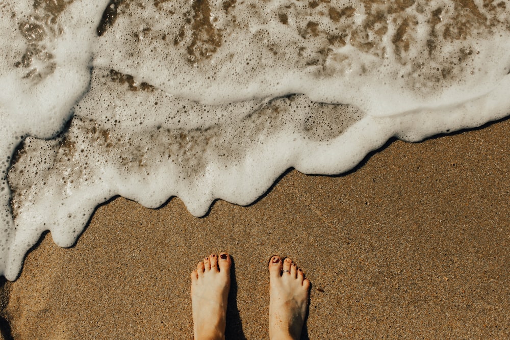 person's feet on seashore