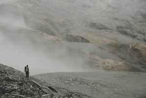 A solo backpacker standing on a misty mountain ridge, gazing at the sunrise over rolling hills.