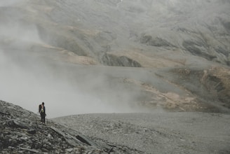 A hiker standing on a mountain trail with a backpack.