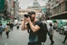 shallow focus photography of man using a DSLR camera