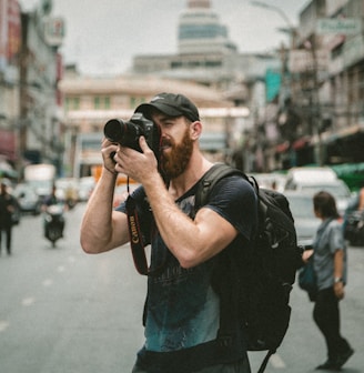 shallow focus photography of man using a DSLR camera