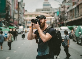 shallow focus photography of man using a DSLR camera