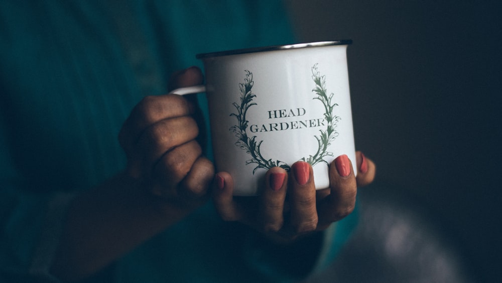 person holding white coffee mug